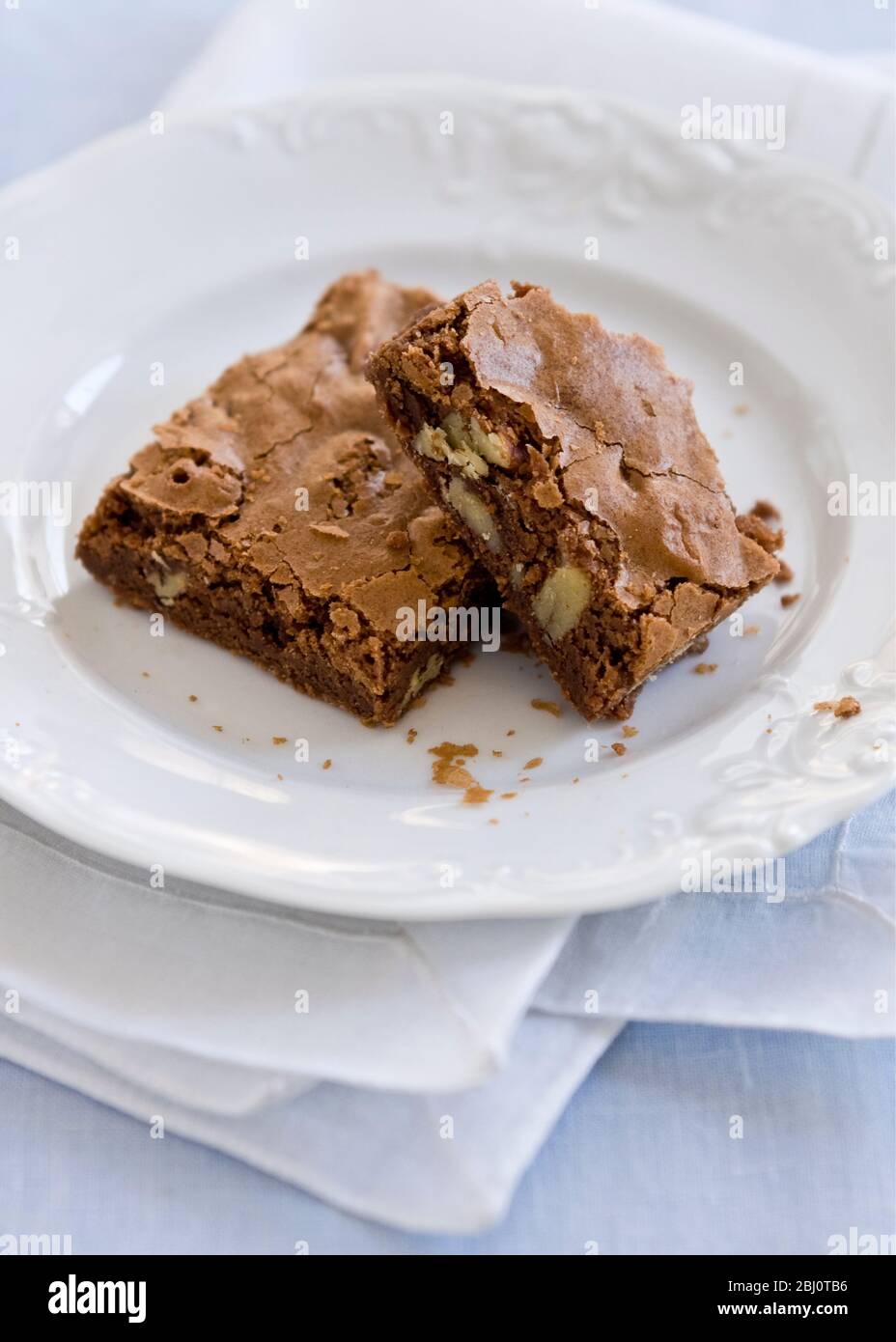 Brownie di nocciole al cioccolato su piastra bianca con tovagliolo di organza bianco - Foto Stock