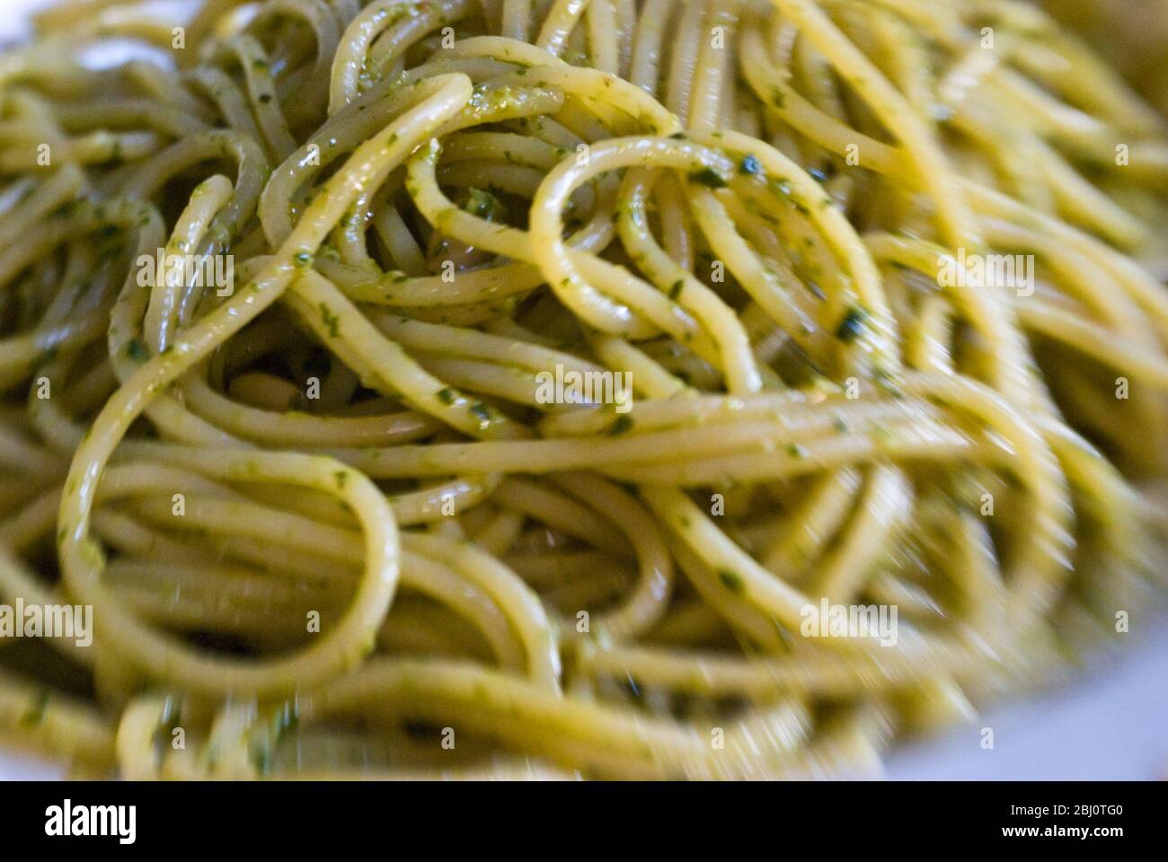 Piatto di spaghetti al pesto di coriandolo e freddo con pinoli. Ripresa con lente Lensbaby per un effetto sfocato. - Foto Stock