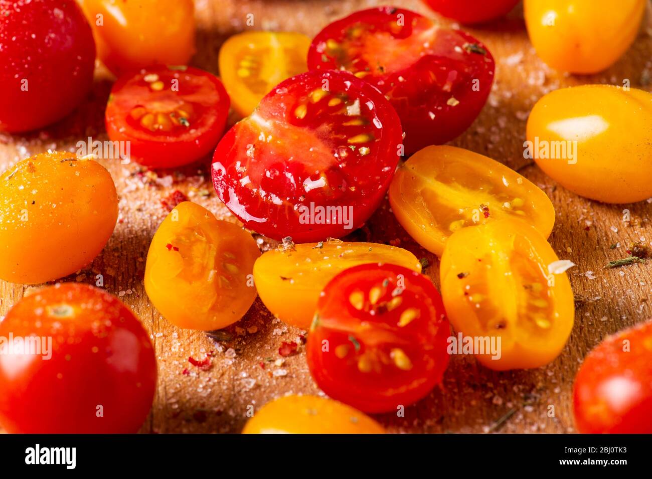 Foto ravvicinata di diverse cultivar di pomodori su un asse di legno. Pomodori multicolore. Foto Stock
