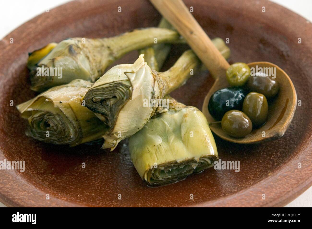 Carciofi italiani alla griglia e marinati su piatto marrone - Foto Stock