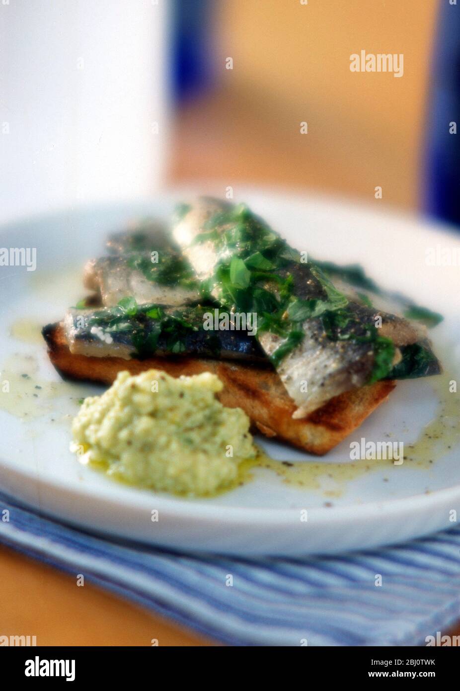 Sardine fresche su pane tostato con erbe tritate e condimento di erbe - Foto Stock