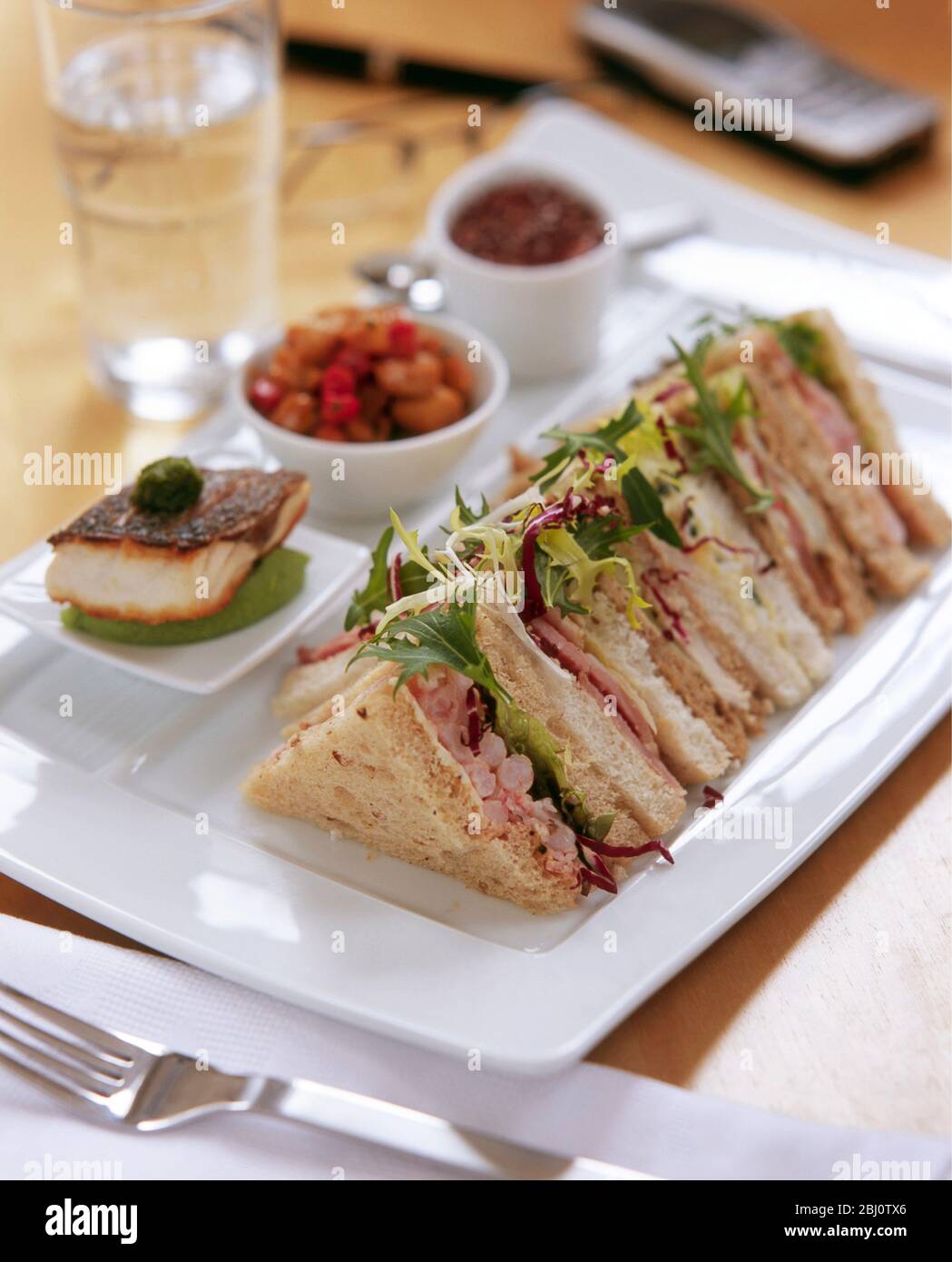 Un piatto executive per un pranzo di lavoro, con panini, pesce alla griglia, insalata di verdure e un piatto accuratamente organizzato - Foto Stock