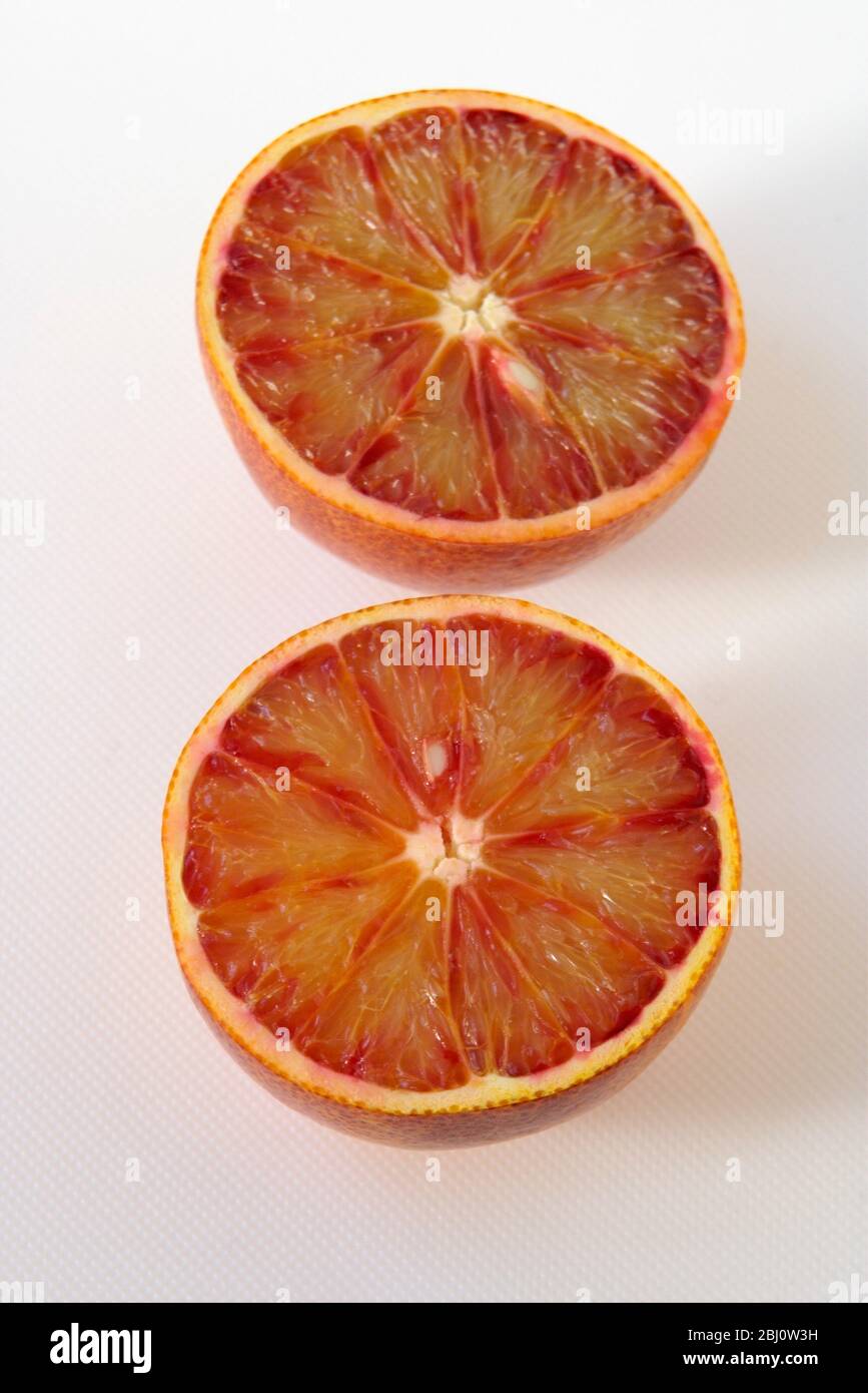Arance, tagliate a metà su superficie bianca - Foto Stock
