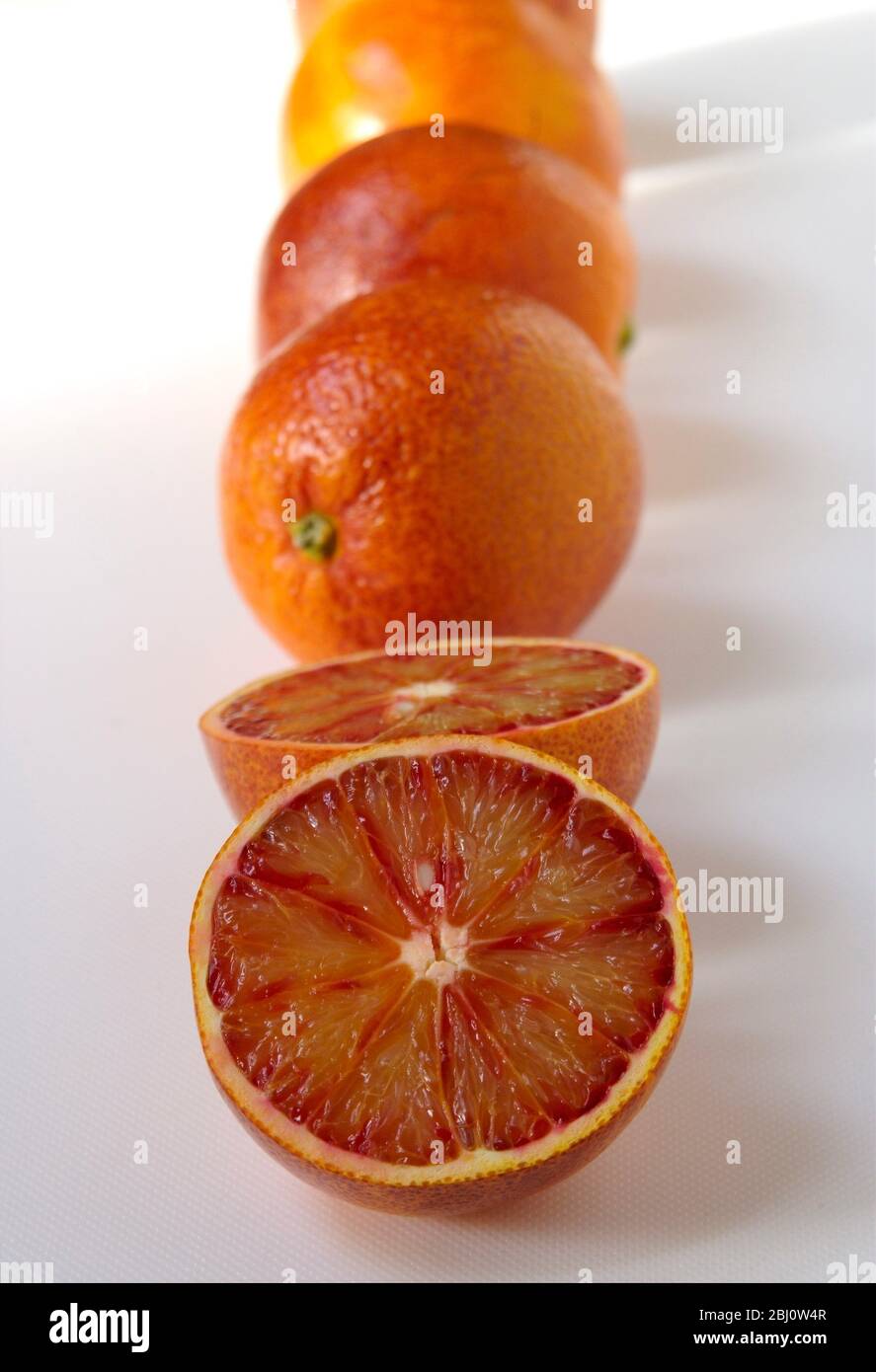 Arance, tagliate e intere su superficie bianca - Foto Stock