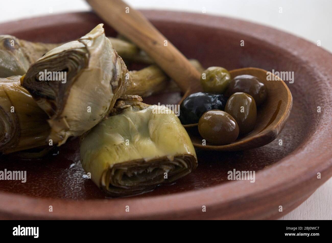 Carciofi italiani alla griglia e marinati su piatto marrone - Foto Stock
