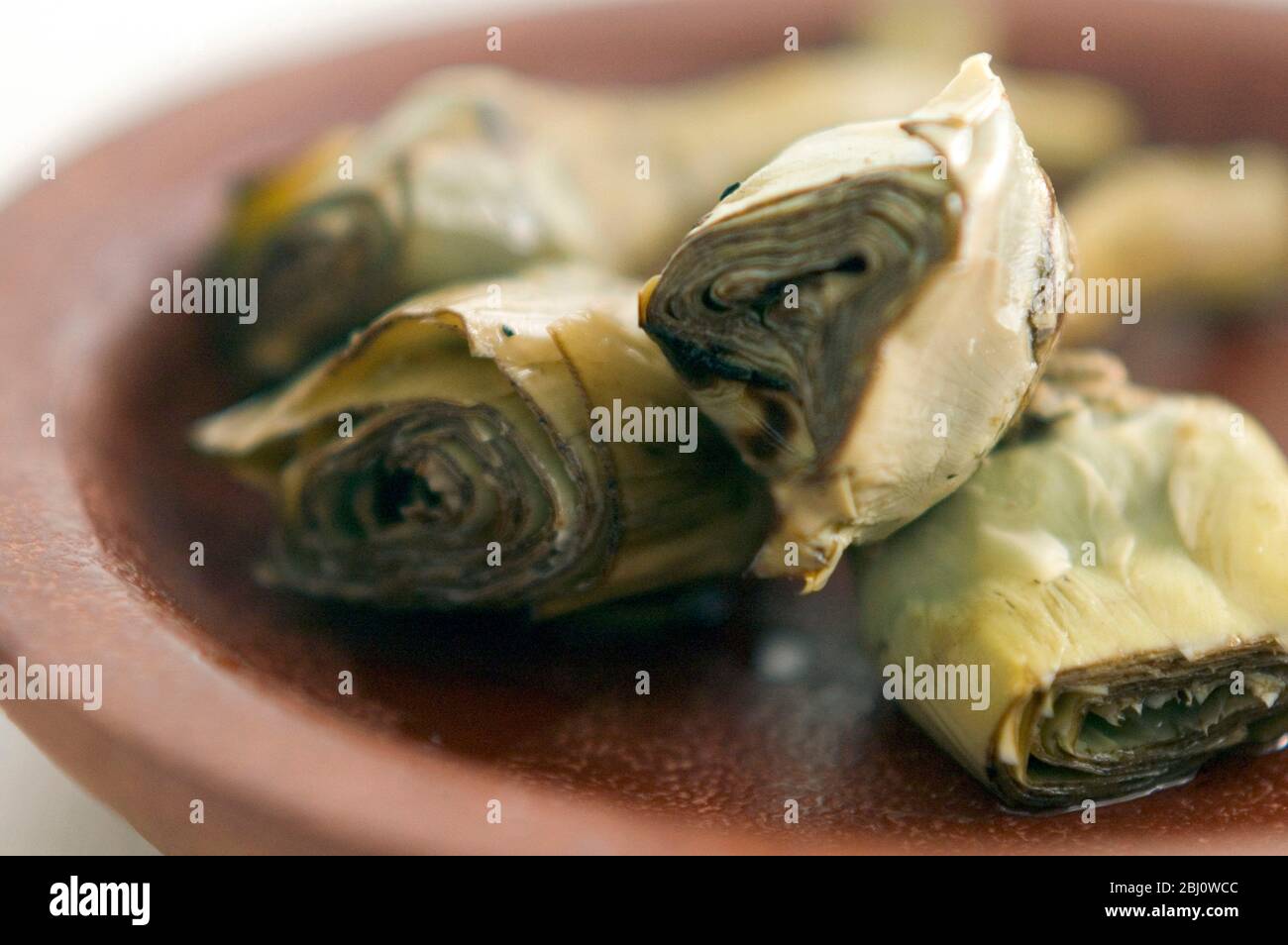 Carciofi italiani alla griglia e marinati su piatto marrone - Foto Stock