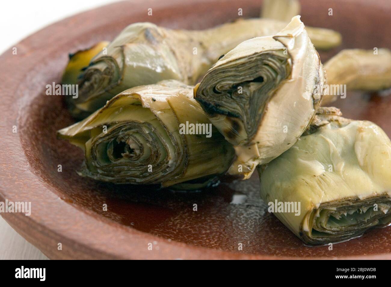 Carciofi italiani alla griglia e marinati su piatto marrone - Foto Stock