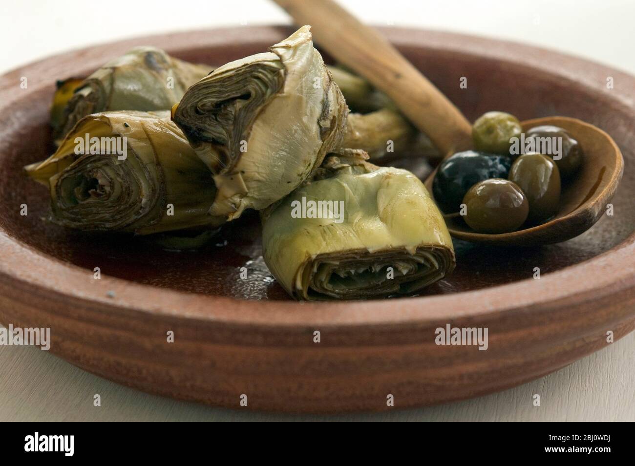 Carciofi italiani alla griglia e marinati su piatto marrone - Foto Stock