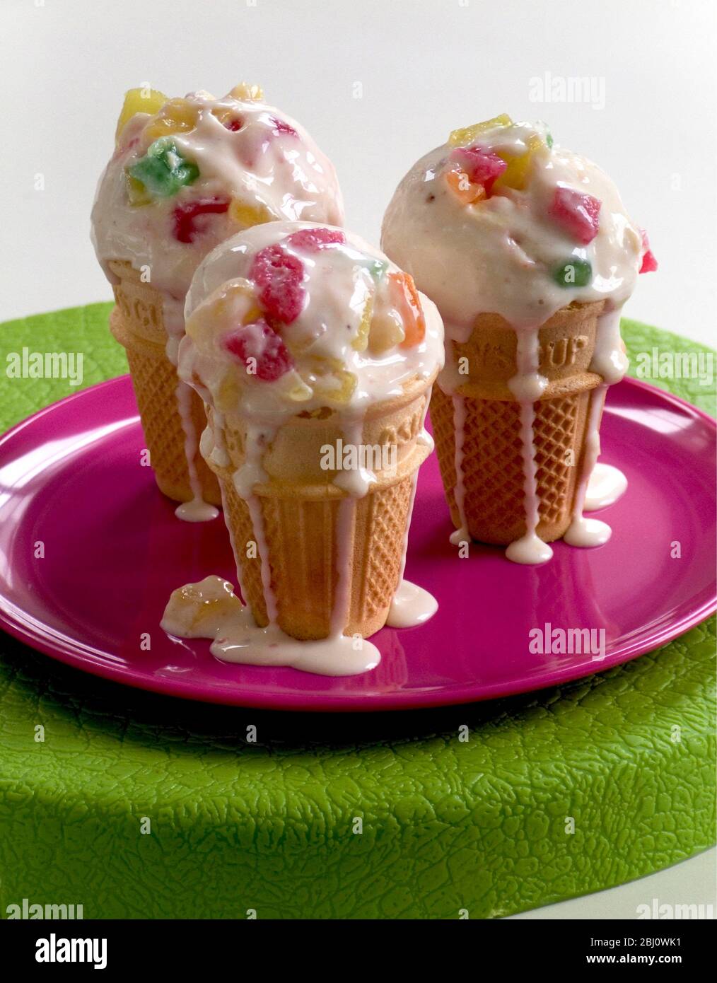 Tutti frutti ghiaccio ceam leggermente fondente in coni stand up su piastra rosa - Foto Stock