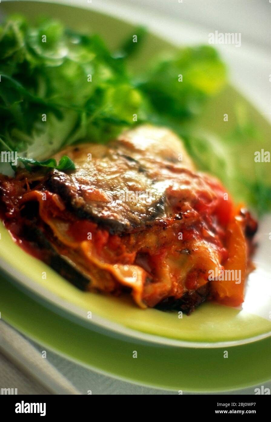 Porzione di lasagne vegetariane servita con insalata verde - Foto Stock