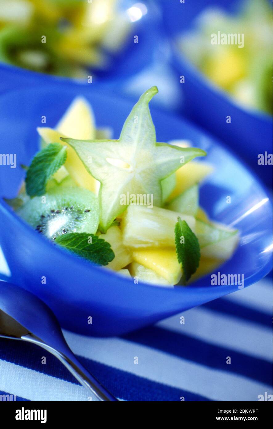 Macedonia di frutta fresca con frutta a stella e kiwi in ciotola blu - Foto Stock