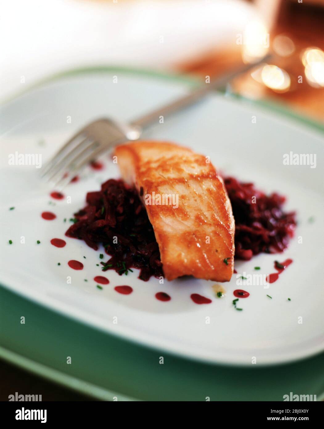 Filetto di salmone alla griglia su insalata di barbabietole grattugiate crude su piatto bianco - Foto Stock