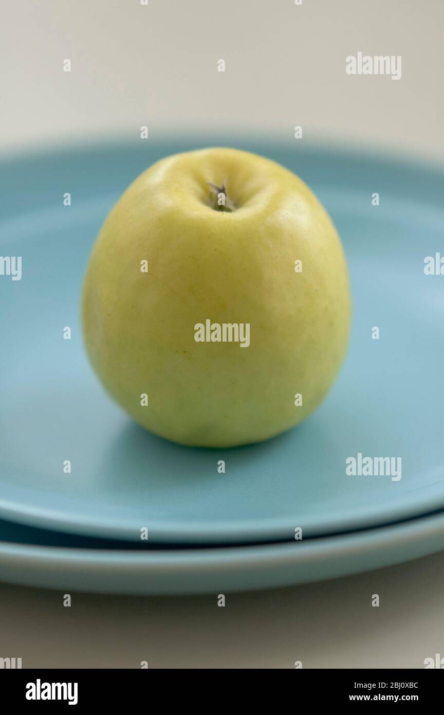 Mela verde gialla su piatti blu - Foto Stock