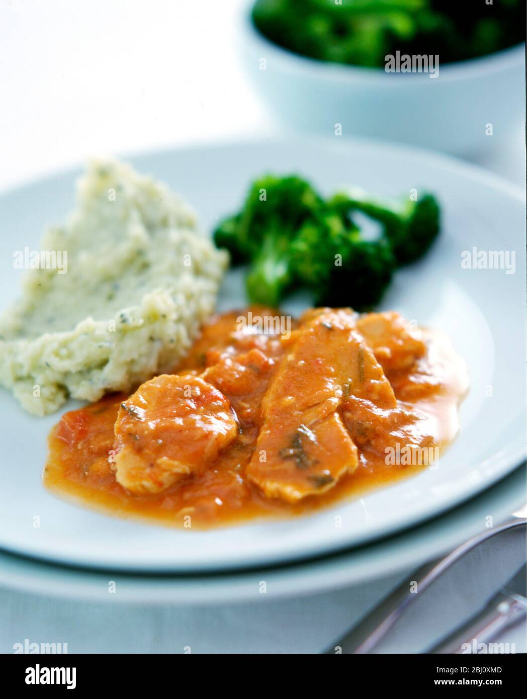 Maiale cotto con una salsa cremosa di pomodoro servito con purè di patate e broccoli - Foto Stock