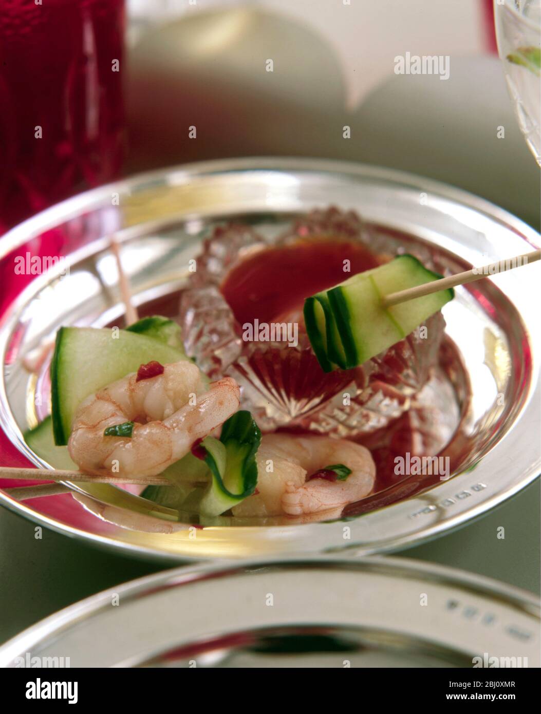 Piccolo piatto d'argento di tartine - gamberi e strisce di cetrioli su bastoncini da cocktail con condimento al peperoncino - Foto Stock