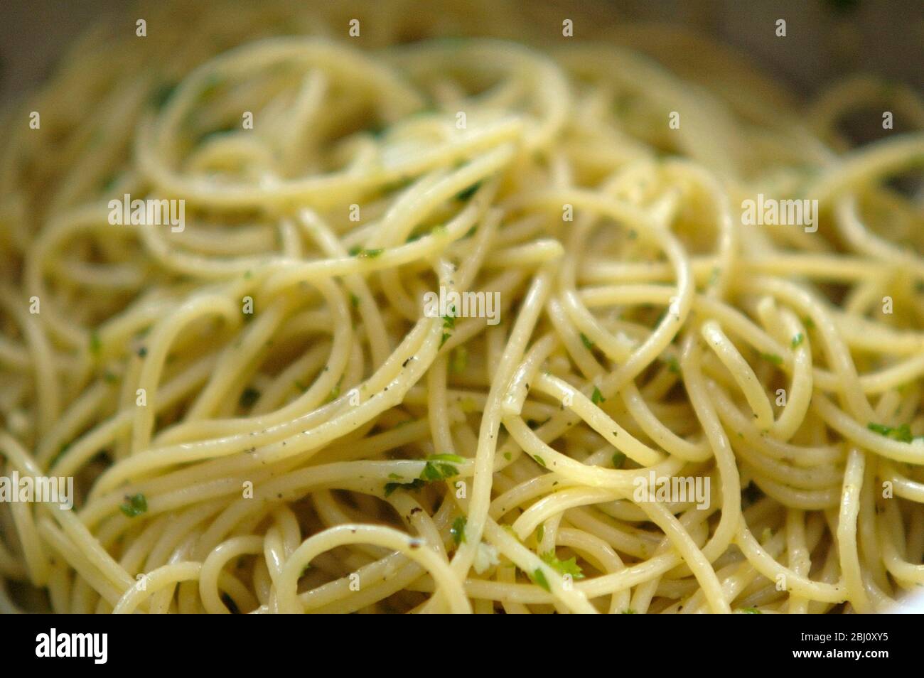 Spaghetti appena cotti e conditi semplicemente con olio d'oliva, sale e pepe nero e prezzemolo tritato - Foto Stock