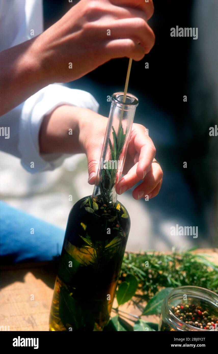 Usando erbe fresche e condimenti per fare olio di oliva di aroma - Foto Stock