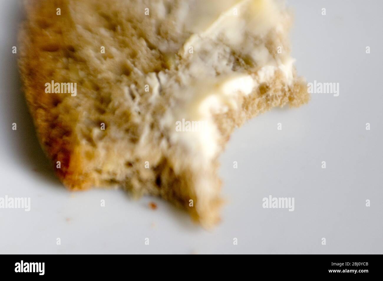 Pezzo di pane al burro con morsi - girato con l'obiettivo lensbaby per un effetto di messa a fuoco breve - Foto Stock