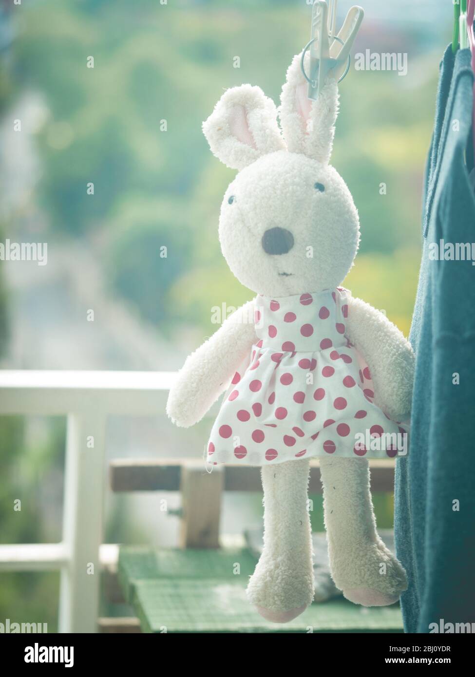 Una bambola di coniglio appesa sul clothesline, la bambola di coniglio che indossa un abito a pois di polka Foto Stock