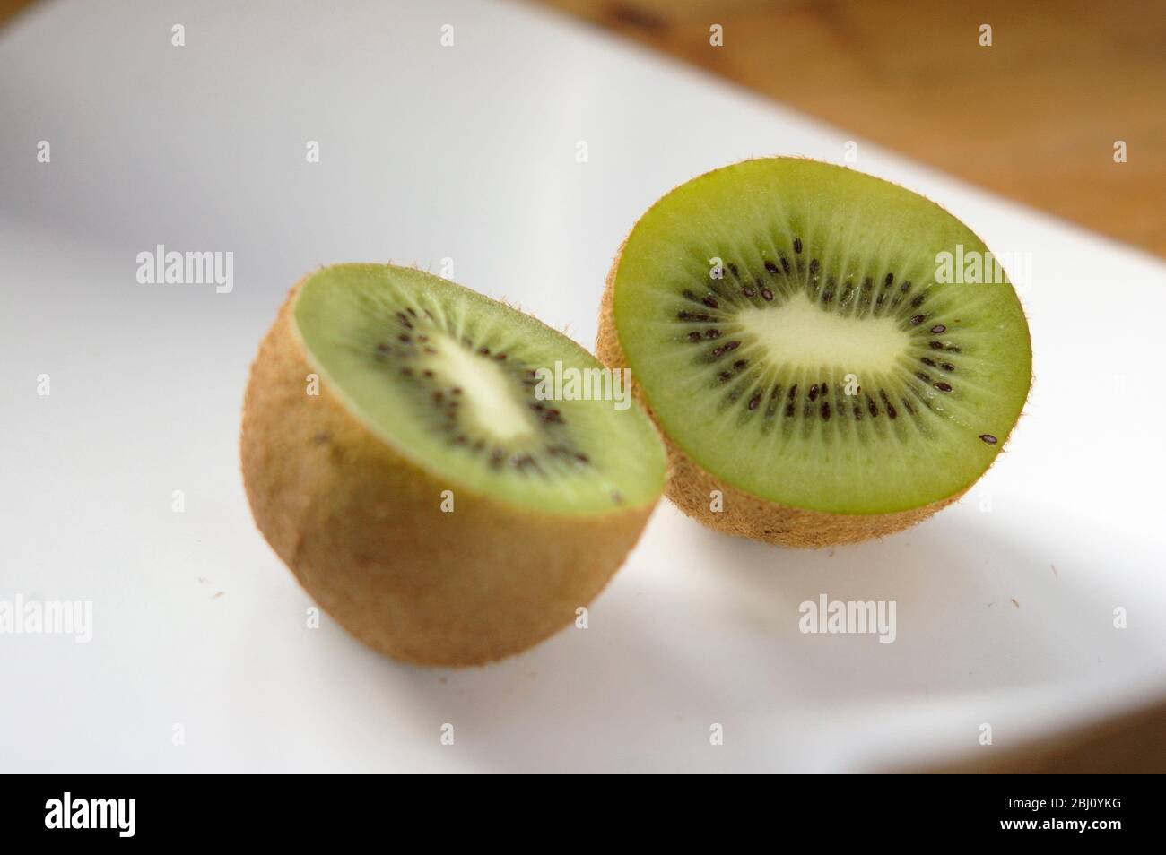 Frutta Kiwi dimezzata per mostrare all'interno struttura e struttura su superficie ceramica bianca 5 - Foto Stock
