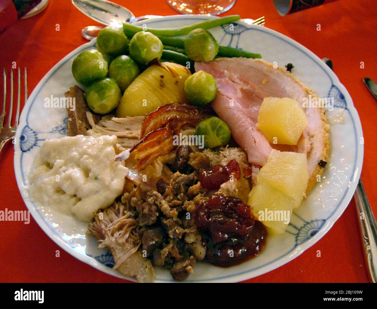 Cena di Natale completa con tacchino, prosciutto, salsa di pane, farcitura, cavolini di bruxelles, sausagemeat, ananas, patate arrosto, salsa di mirtilli su dani Foto Stock