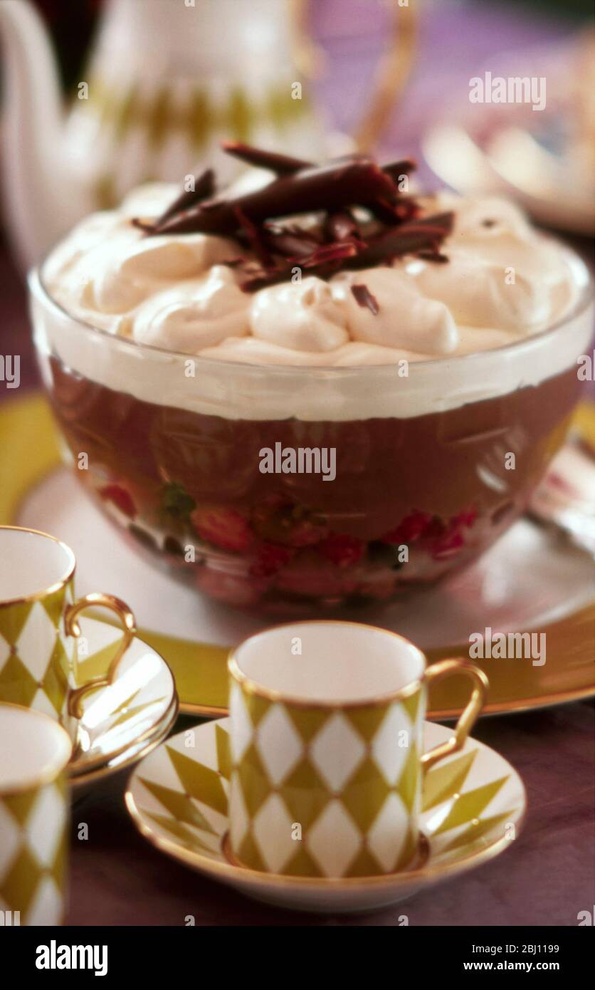 Trifle al cioccolato con panna montata e tazze di caffè dopo cena - Foto Stock