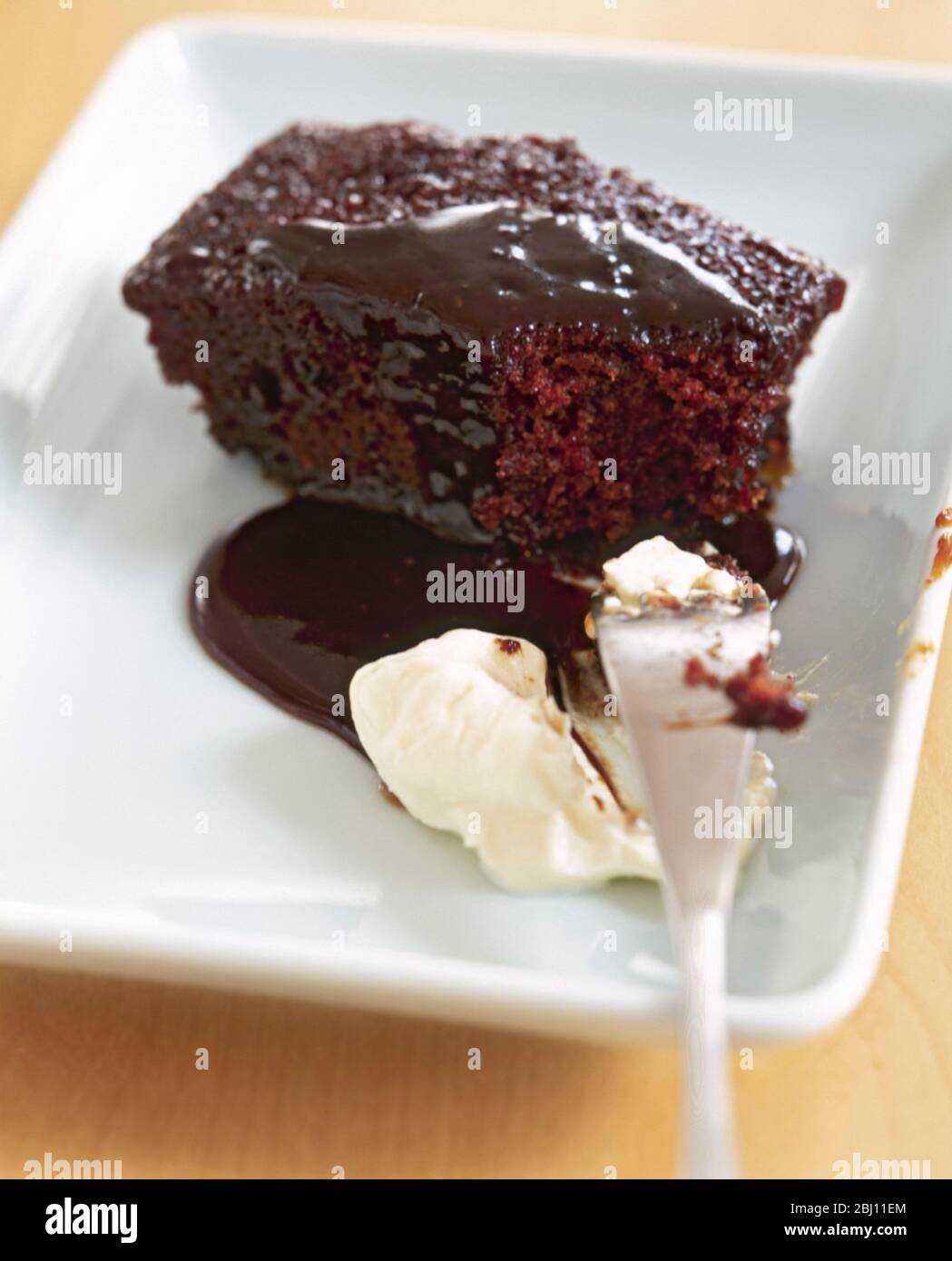 Budino di spugna al cioccolato con salsa appiccicosa e crema - Foto Stock