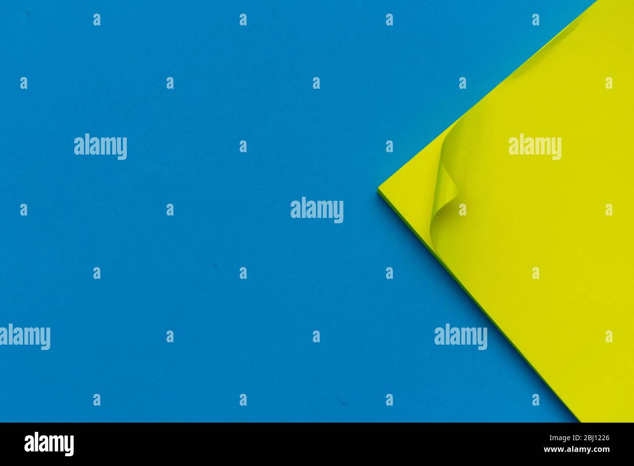 Giallo brillante affisso nota a destra su sfondo blu brillante piatto per l'organizzazione di istruzione o business e promemoria concetti. Foto Stock