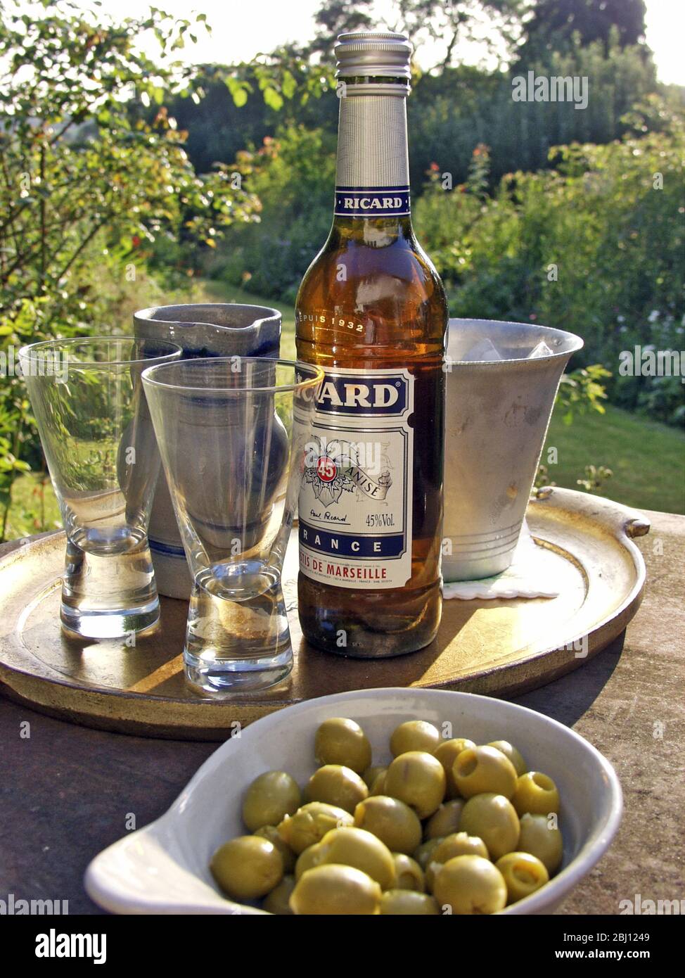 Due bicchieri di pernod tipo bevanda che si versa al sole della sera - Foto Stock