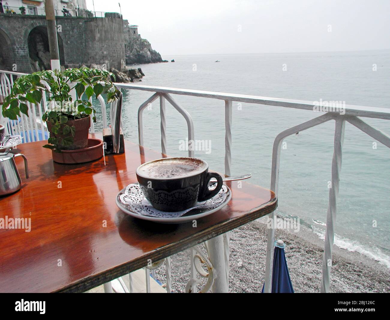 Tazza di cappuccino al tavolo del ristorante a lato della spiaggia, Amalfi, Italia - Foto Stock