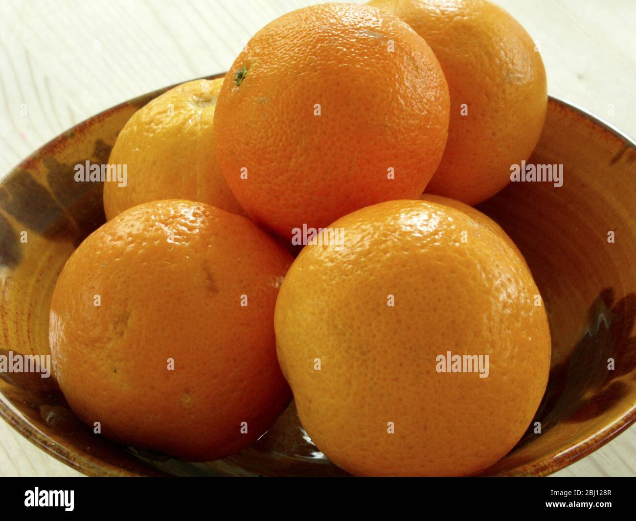 Ciotola in ceramica con cinque arance fresche - Foto Stock