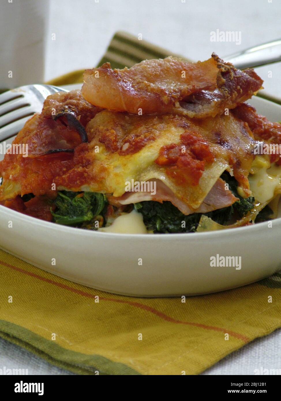Porzione di lasagne con prosciutto di parma, spinaci e formaggio - Foto Stock