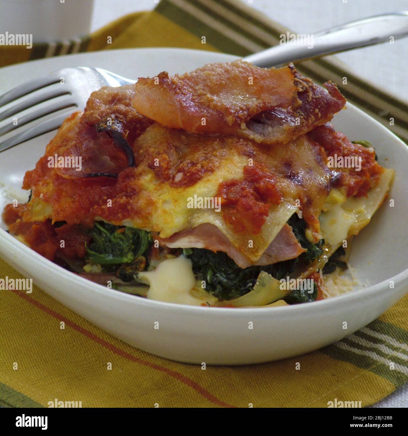 Porzione di lasagne con prosciutto di parma, spinaci e formaggio - Foto Stock