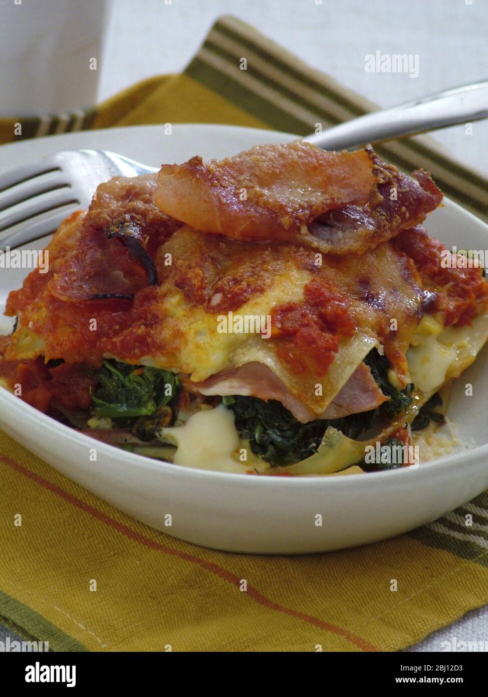 Porzione di lasagne con prosciutto di parma, spinaci e formaggio - Foto Stock