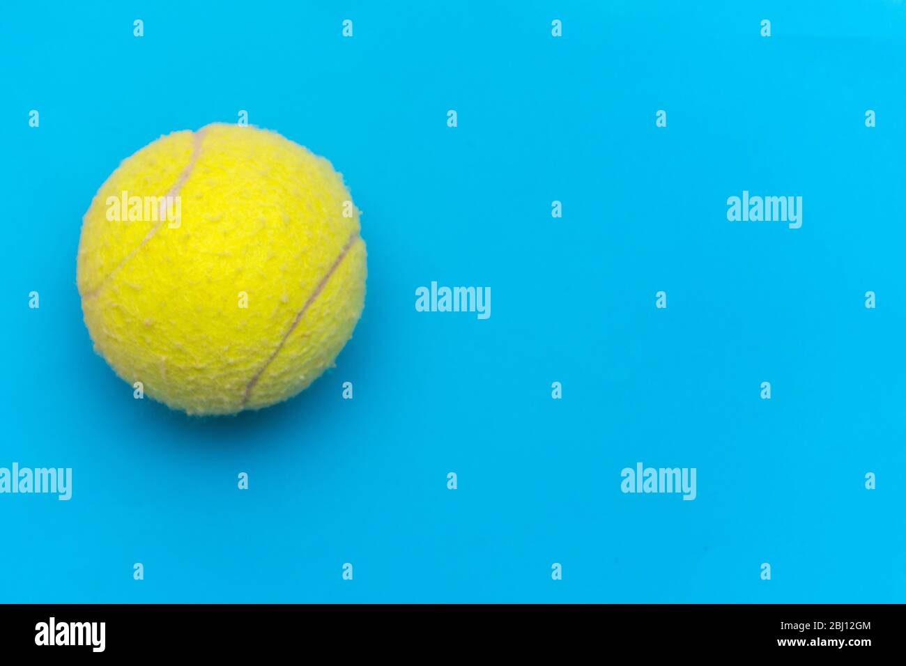 Palla da tennis giallo brillante su un solido fondo piatto blu acqua simboleggia sport e attività con spazio per le copie. Foto Stock