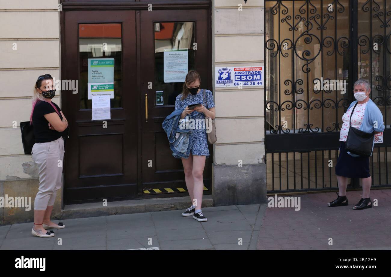 Cracovia. Cracovia. Polonia. Coronavirus pandemico. Persone mascherate che aspettano per strada davanti alla banca per entrare in ufficio. Foto Stock