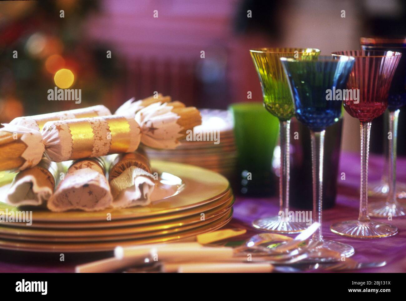 Tavolo natalizio con occhiali a stelo lungo e cracker colorati - Foto Stock