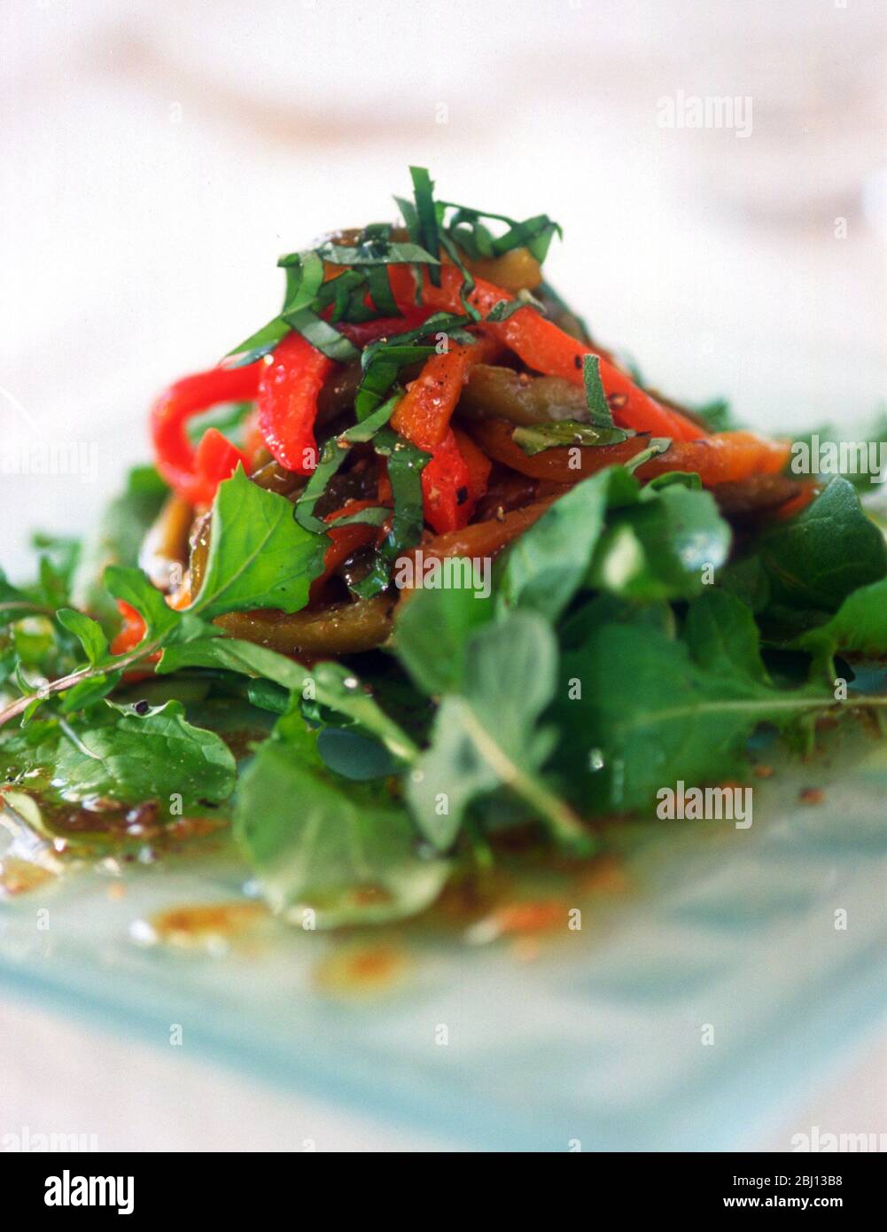 Insalata di foglie miste e peperoni arrosto su piatto di vetro - Foto Stock