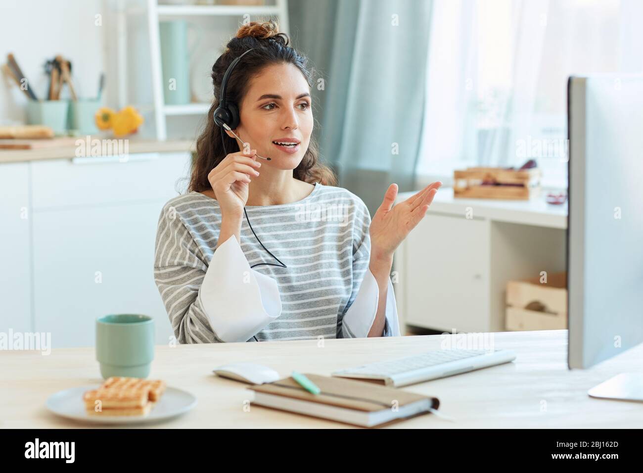 Una donna d'affari moderna che trascorre la mattina a casa parlando con i suoi colleghi utilizzando l'app per videoconferenze Foto Stock