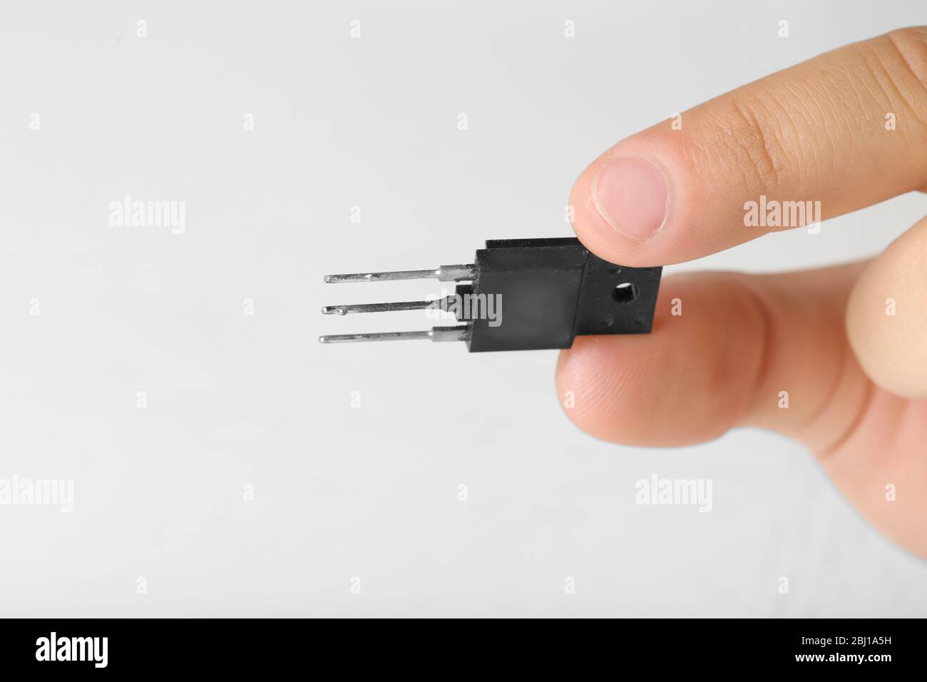 Dita maschio che tengono il microchip isolato su bianco Foto Stock