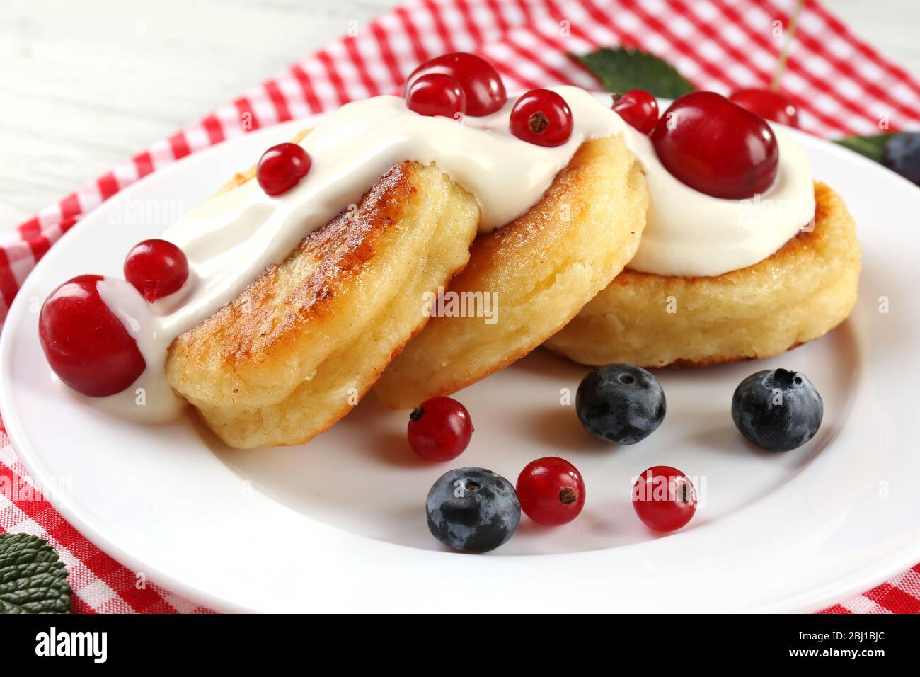 Frittelle di formaggio casolare con frutti di bosco in piatto, primo piano Foto Stock