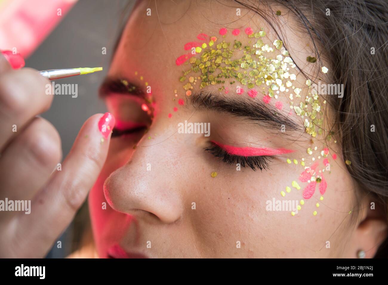 Trucco artista applicare glitter al viso della donna. Foto Stock