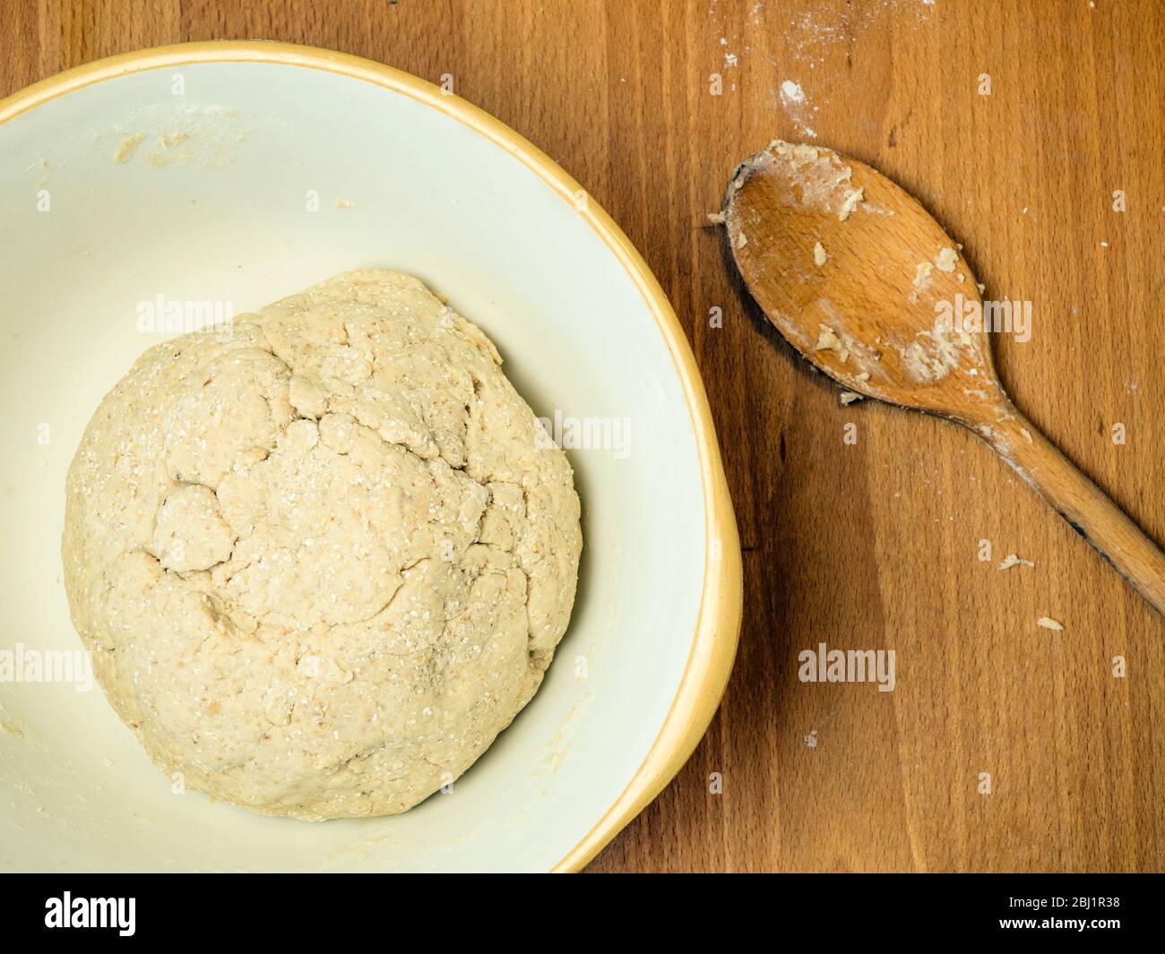 Pasta di pane OAT fatta forma forte farina di pane bianco con schiuma di avena e avena arrotolata in una terrina di miscelazione con un cucchiaio di legno Foto Stock