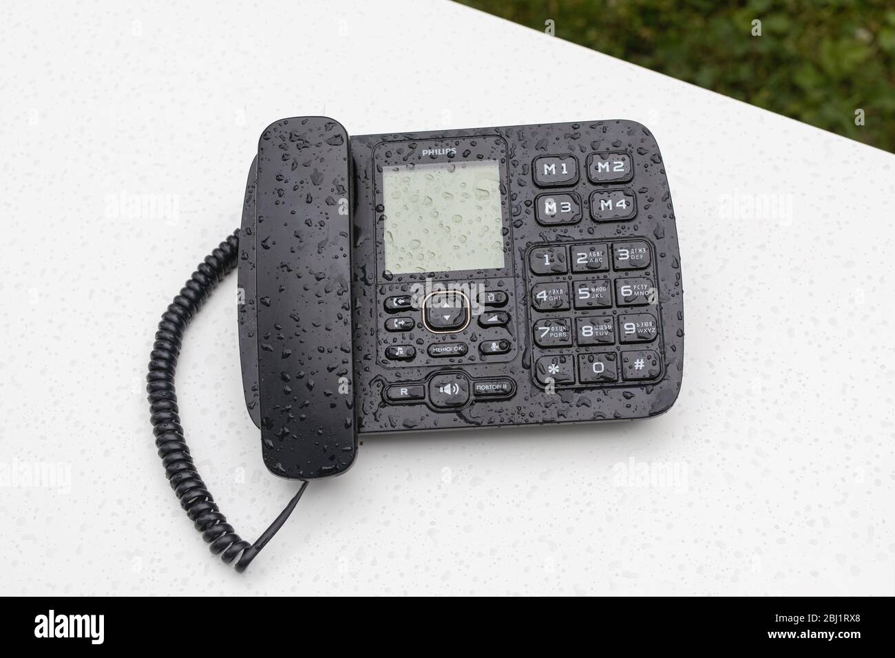 Telefono nero fisso da tavolo con toni di tocco su tavolo bianco all'aperto coperto da idranti. Postazione di lavoro remota, comunicazione, ufficio di lavoro online. Bas Foto Stock