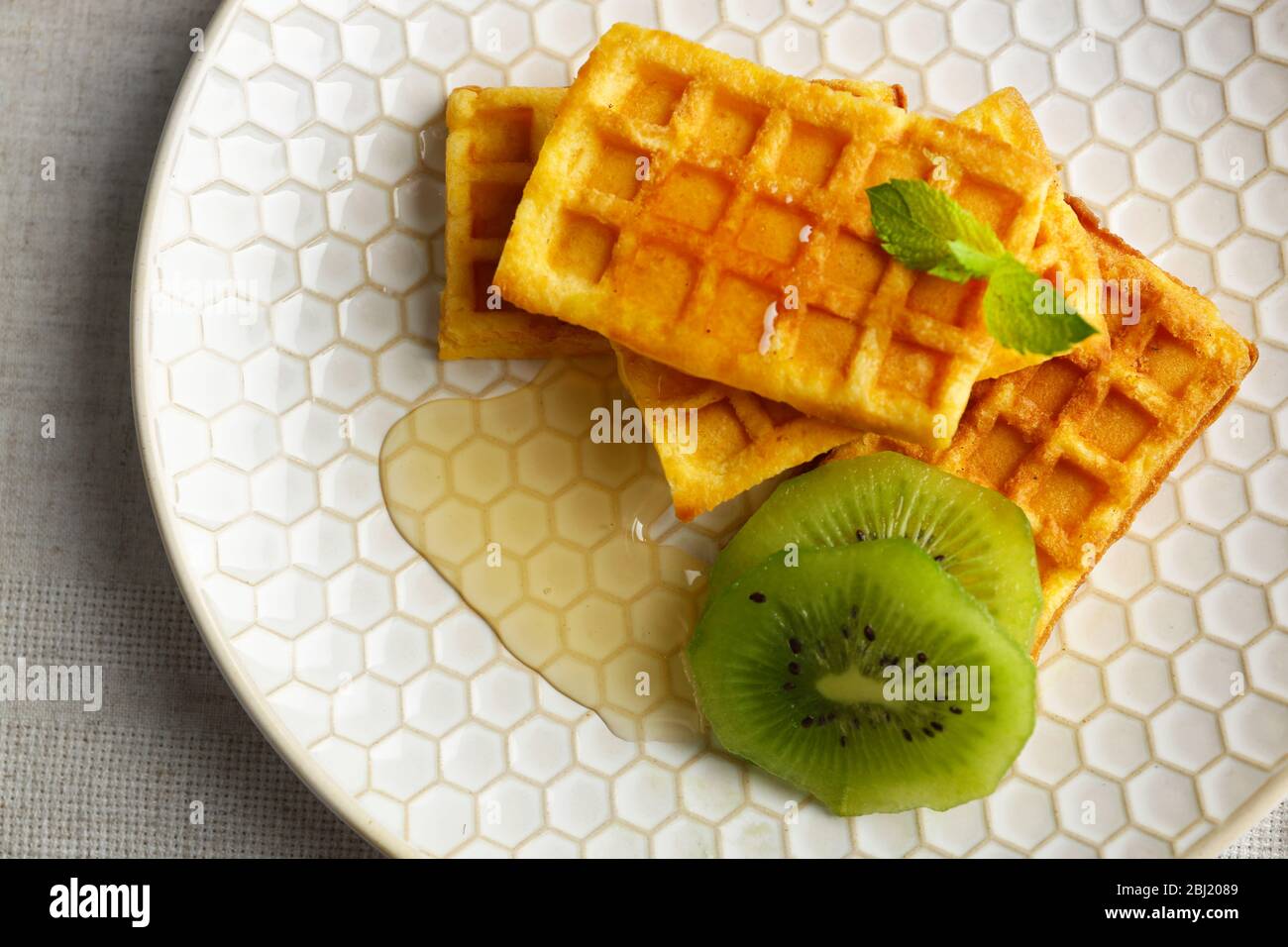 Waffle fatti in casa e kiwi freschi sul piatto, primo piano Foto Stock