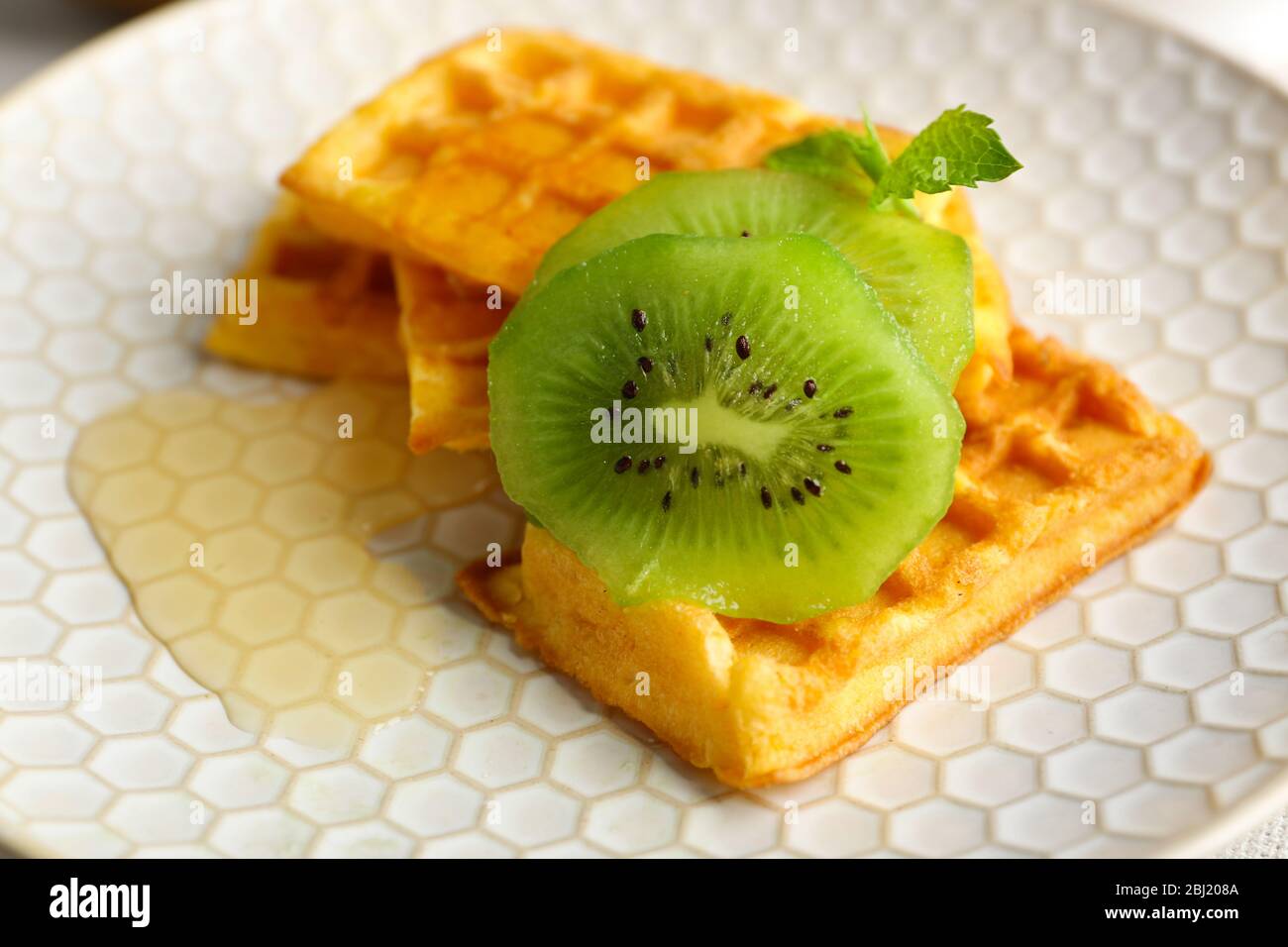 Waffle fatti in casa e kiwi freschi sul piatto, primo piano Foto Stock