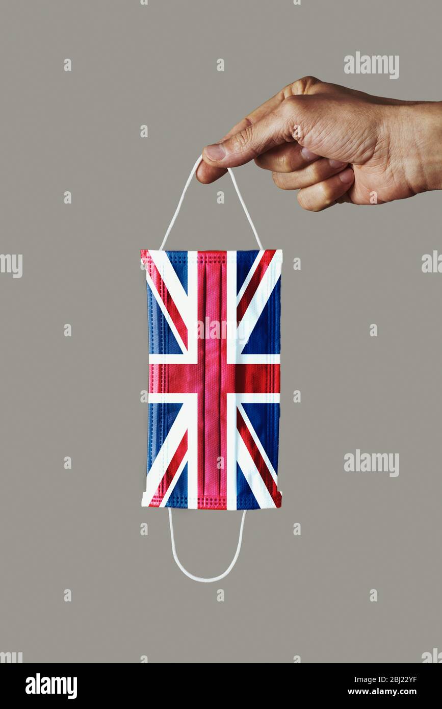 Primo piano di uomo con maschera chirurgica modellata con bandiera del Regno Unito su sfondo grigio Foto Stock