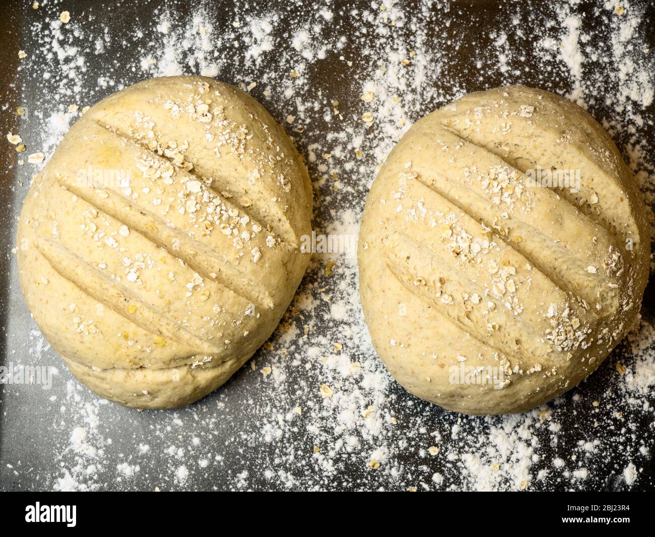 Due focacce di pane provate pronte per la cottura su una lamiera infarinata Foto Stock