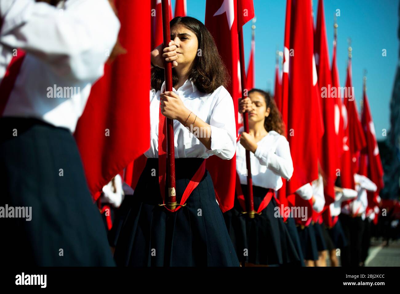 Izmir, Turchia - 29 ottobre 2019. Bandiere rosse turche e giovani studenti donne che li tengono alla cerimonia Cumhuriyet Square Alsanmak , Izmir. In Repubblica Foto Stock