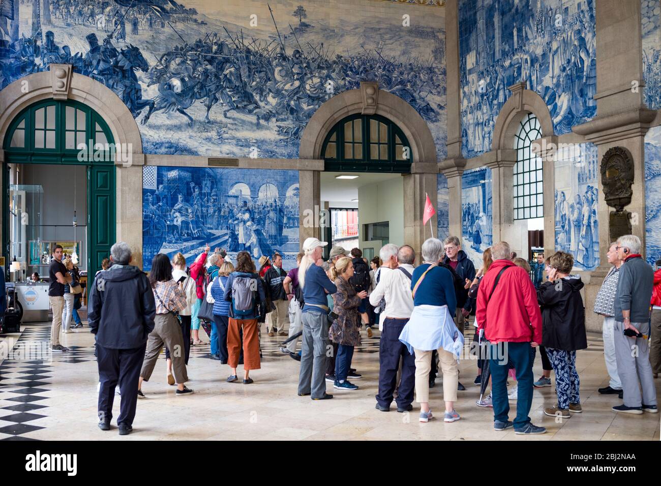 I turisti ammirano le piastrelle tradizionali portoghesi blu e bianche della parete della stazione ferroviaria Sao Bento a Porto, Portogallo Foto Stock